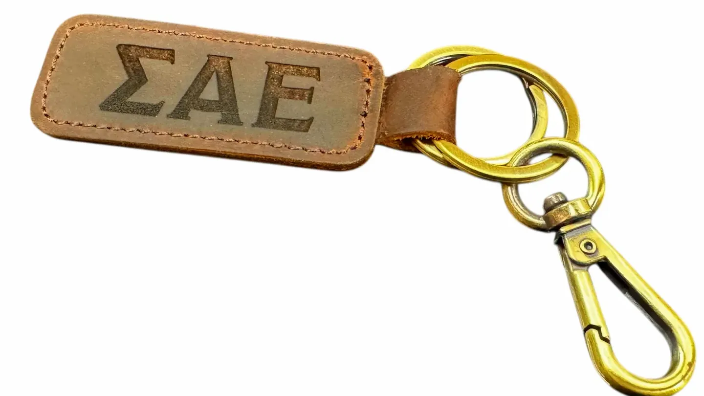 Leather keychain engraved with Greek letters and attached to a metal clip